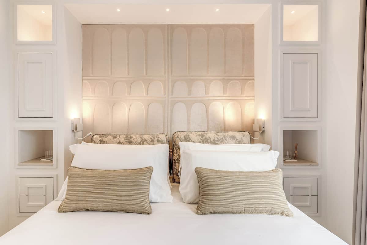Una habitación de hotel con una cama grande, dos mesitas de noche y un cabecero decorativo.