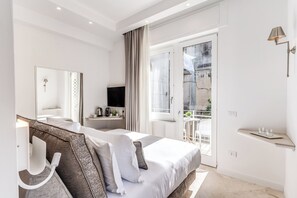 A modern hotel room with a large bed, a flat-screen TV, a bedside table, a mirror, and a balcony with a view of the city. - Diff'rent Souls Rooms (Sorrento)
