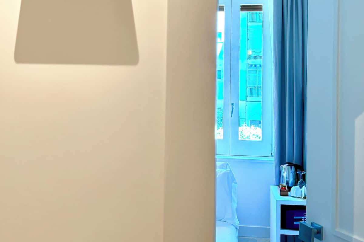 Una habitación de hotel con una cama, una mesita de noche y una ventana con cortinas.