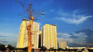 Un edificio alto de varios pisos, rodeado por un cielo azul despejado con algunas nubes.