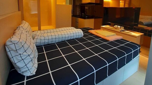 Una sala de estar moderna con sofá, televisión y zona de cocina.