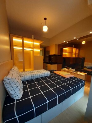 Una sala de estar moderna con sofá, televisión y zona de cocina.