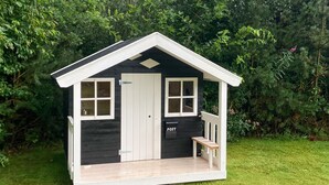 A small, two-story wooden structure with a white door, two windows, and a mailbox labeled "POST". - 3 bedroom cozy home in Oksbøl (Oksbøl)