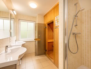 Ein Badezimmer mit Duschkabine aus Holz, einem großen Fenster und einem weißen Waschbecken.