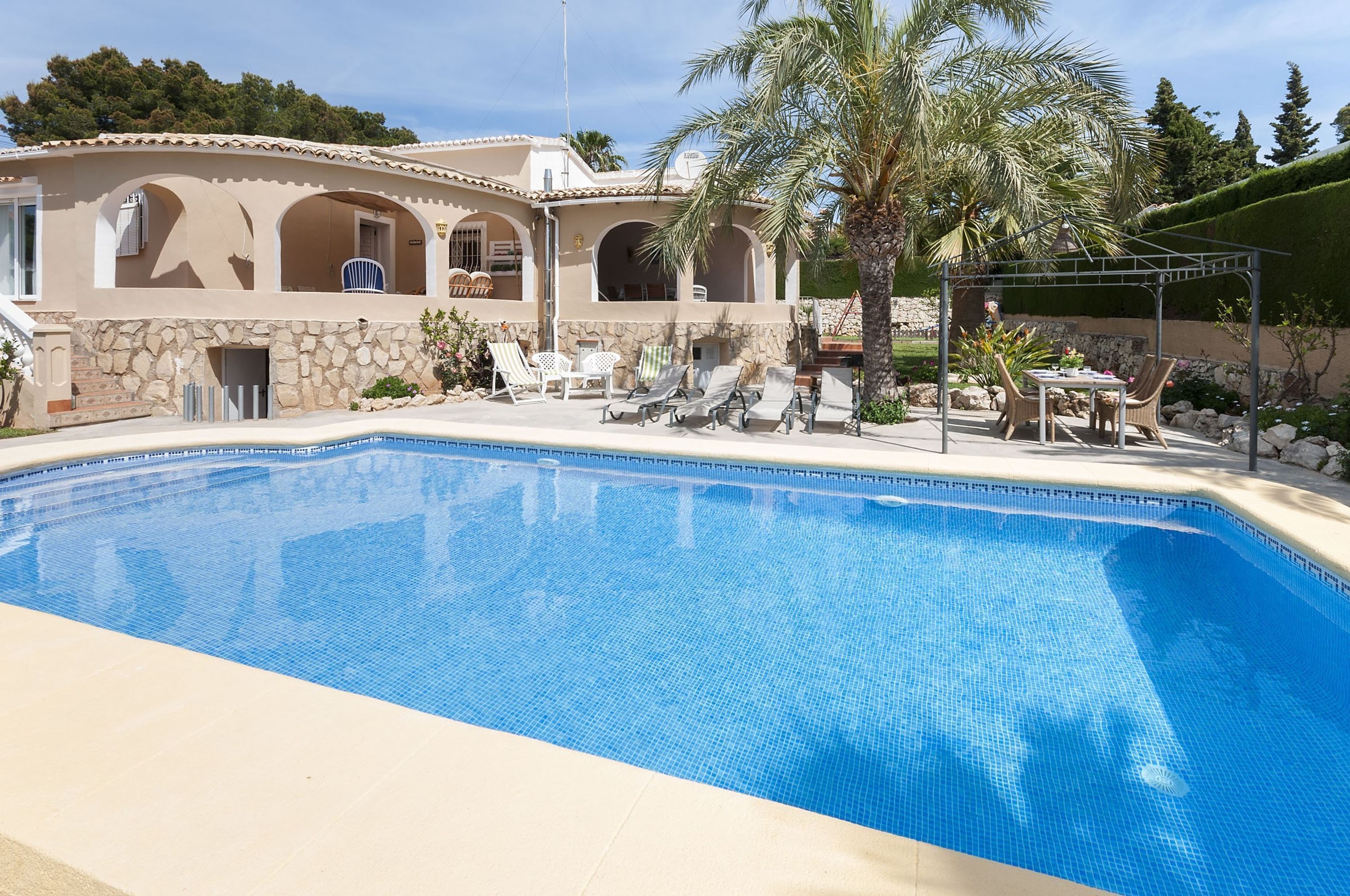 Une piscine avec des chaises longues et une pergola.