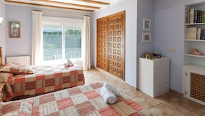 A bedroom with two beds, a wooden wardrobe, a bookshelf, and a window with curtains. - Frederic in Balc n del Mar (Javea)