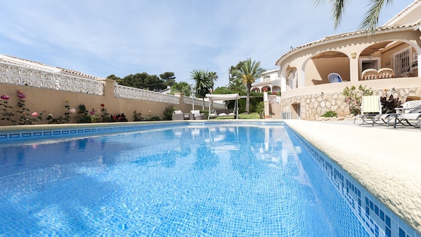 A swimming pool with clear blue water, surrounded by a white fence and palm trees. - Frederic in Balc n del Mar (Javea)