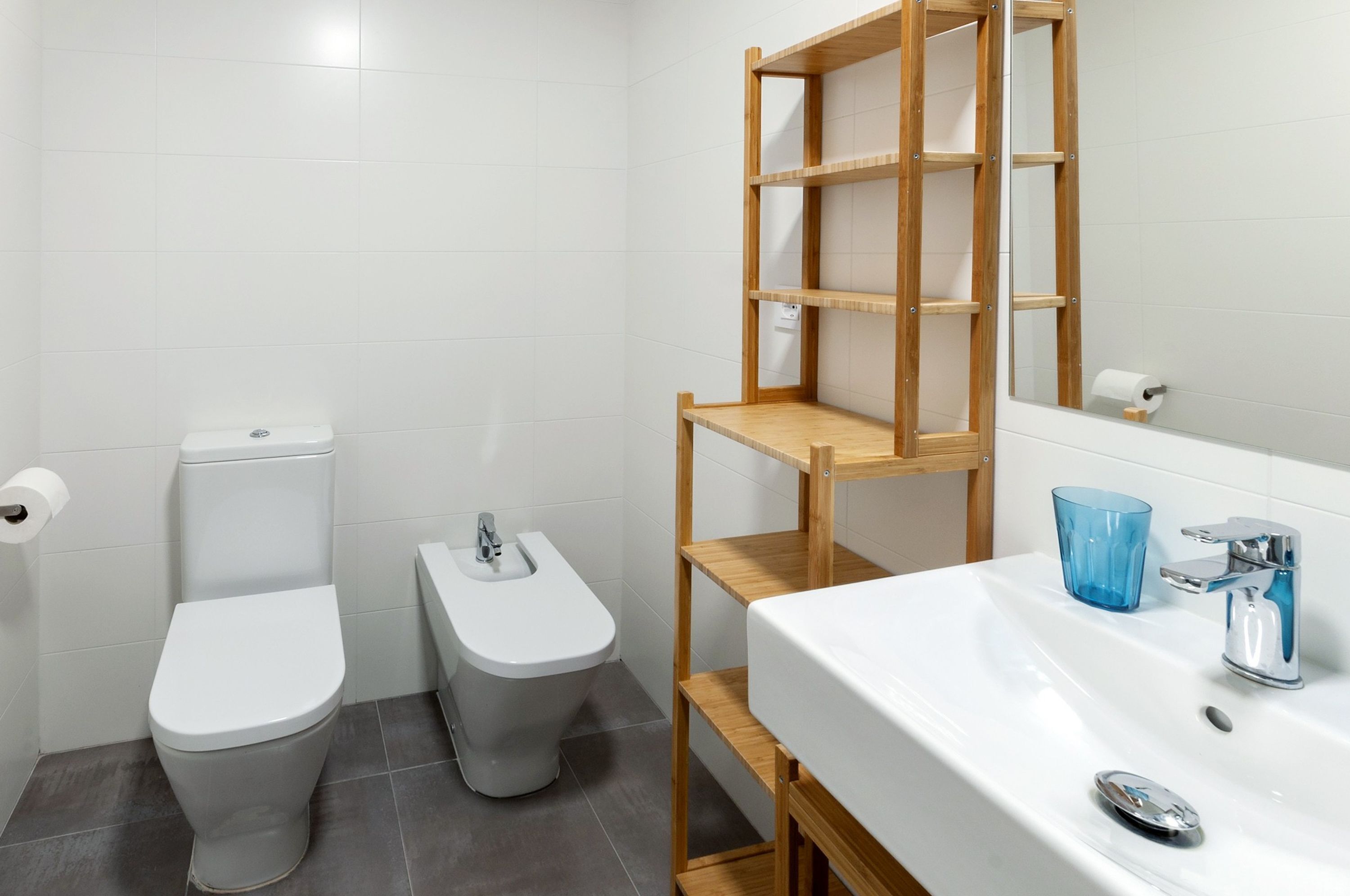 A bathroom with a toilet, bidet, and a sink with a mirror.