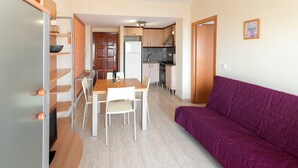 A compact living space with a dining area, kitchenette, and a purple sofa. - Infante in Grau i Platja (Gandia)