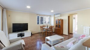A living room with a flat-screen TV, a dining table with chairs, a sofa, and a cabinet. - Golden in Gandia With 3 Bedrooms and 3 Bathrooms (Gandia)