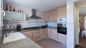 A modern kitchen with a granite countertop, stainless steel sink, wooden cabinets, a built-in microwave, and a range hood. - Golden in Gandia With 3 Bedrooms and 3 Bathrooms (Gandia)