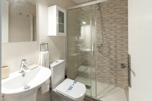 Ein modernes Badezimmer mit einer Duschkabine aus Glas, einem weißen Waschbecken und einer Toilette.