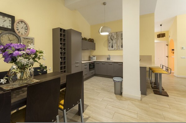 A modern kitchen with grey cabinets, a dining area with a table and chairs, and a vase of flowers on the table. - Flor De Loto in D nia (Denia)