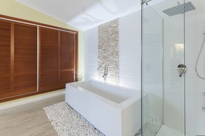 Ein modernes Badezimmer mit einer großen Badewanne, einer gläsernen Duschkabine und Holztüren, die sich verschieben lassen.