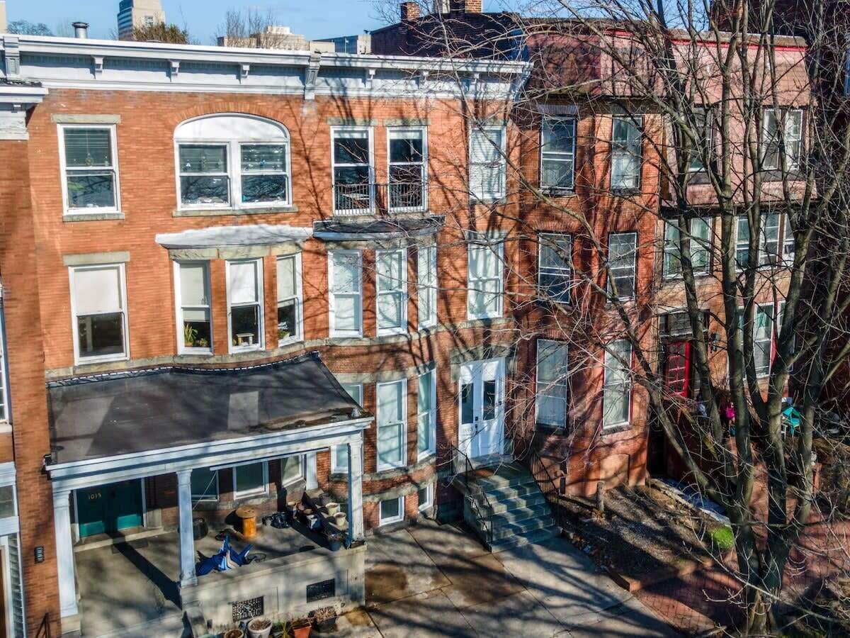 A row of red brick townhouses with a covered front porch and a visible garage.