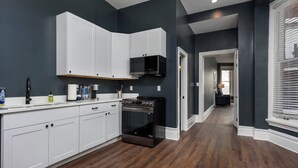 Une cuisine moderne avec des meubles blancs, une cuisinière noire et un mur de couleur sombre.