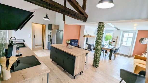 A modern kitchen with a central island, wooden beams, and a dining area with a table and chairs. - Maison Lac et Jardin (Mesnil-Saint-Père)