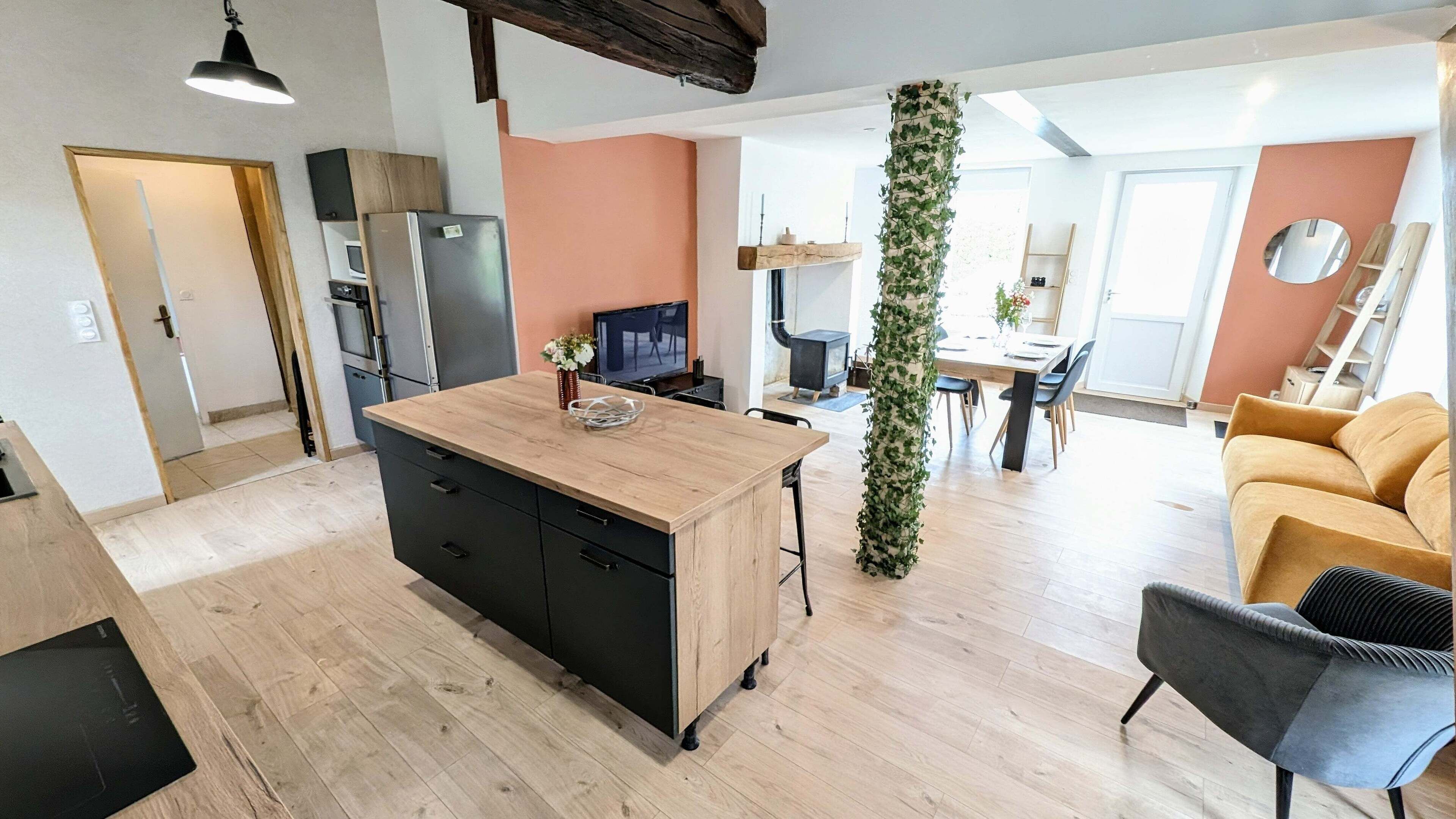 Une cuisine moderne dotée d’un îlot central en bois, d’appareils électroménagers intégrés et d’un coin repas avec une table et des chaises.