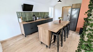 A modern kitchen with a wooden island, black cabinets, and a green-tiled backsplash. - Maison Lac et Jardin (Mesnil-Saint-Père)