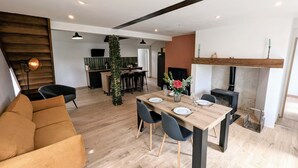 A modern living room with a wooden dining table, black chairs, and a sofa. - Maison Lac et Jardin (Mesnil-Saint-Père)