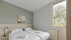 Et soveværelse med to senge, et vindue med udsigt og en radiator.