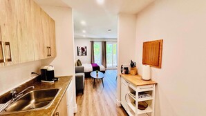 A compact kitchen with a sink, coffee maker, and a small dining area with a table and chairs. - Swimming Pool & Spa | Condo Mont Tremblant 2 (Mont-Tremblant)