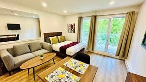 Ein modernes Hotelzimmer mit einer Couch, einem Bett, einem kleinen Tisch und einem Balkon mit Vorhängen.
