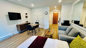 A modern apartment with a bed, a sofa, a dining table, a TV, and a small plant. - Swimming Pool & Spa | Condo Mont Tremblant 2 (Mont-Tremblant)