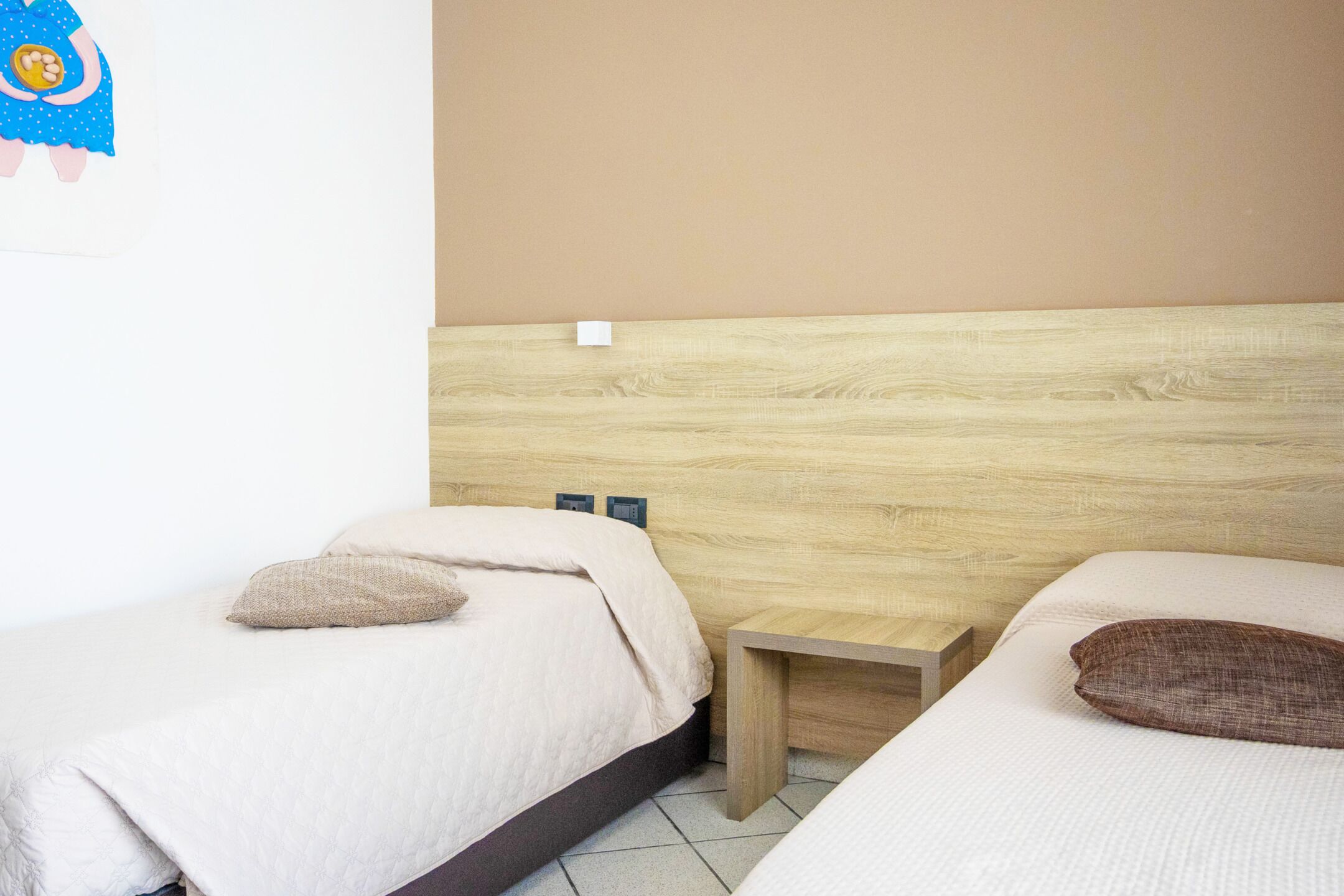 A bedroom with two beds, each with a pillow and a wooden headboard.