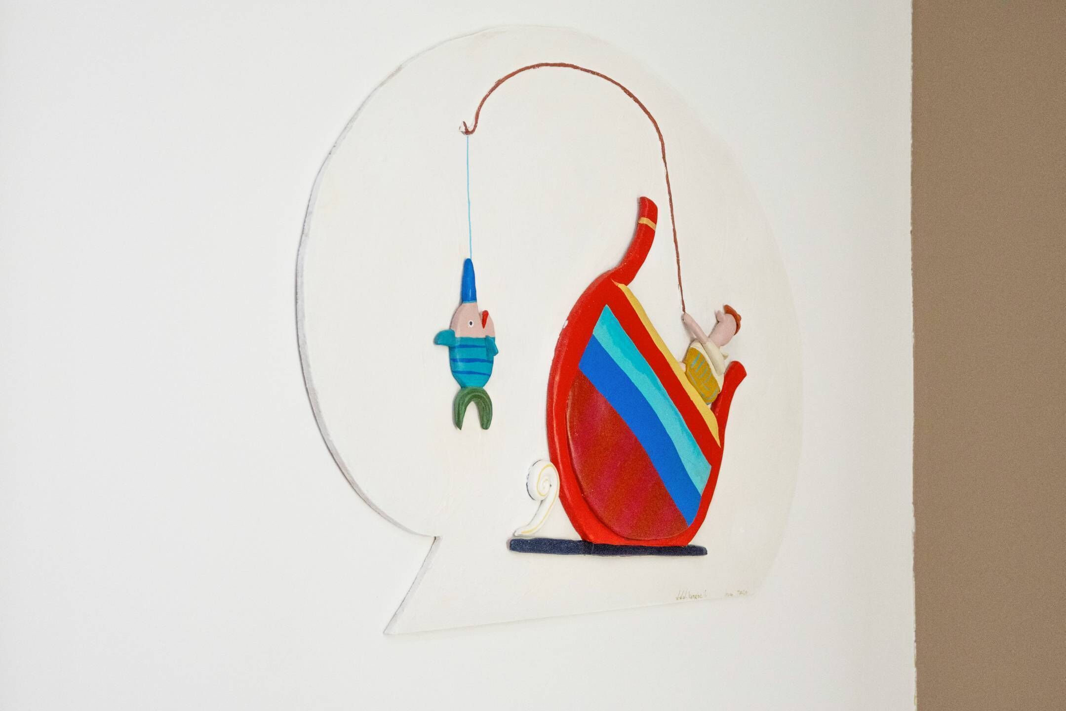 Een cirkelvormig kunstwerk met een figuur in een kleurrijke boot en een hangende figuur.