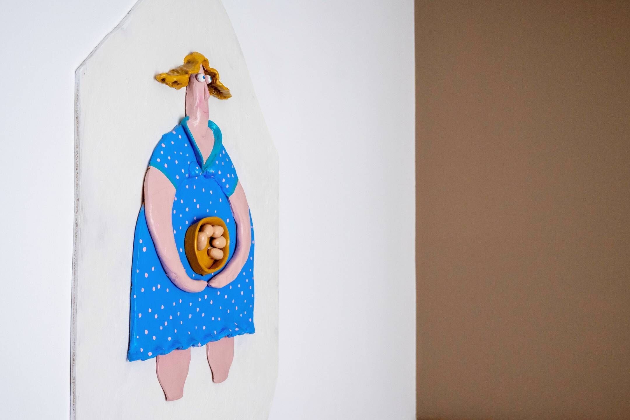 A wall with a painted figure of a woman holding a round object.