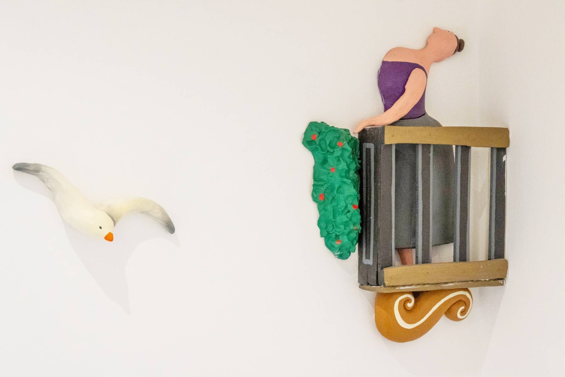 A wall-mounted sculpture of a swan and a figure in a bathtub.