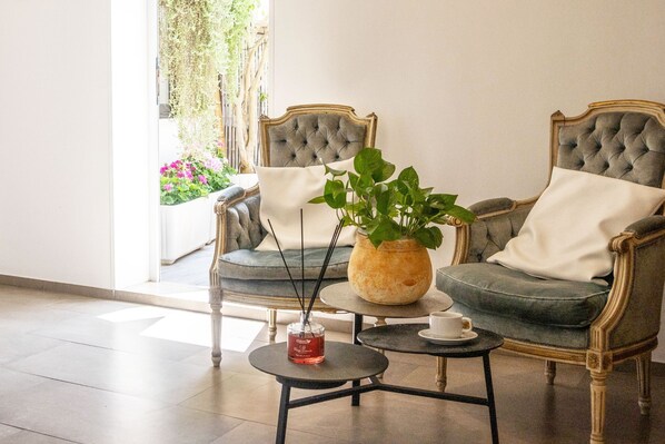 A room with two upholstered chairs, a small round table with a vase and a candle, and a view of greenery outside. - Hotel da Romano (San Foca)