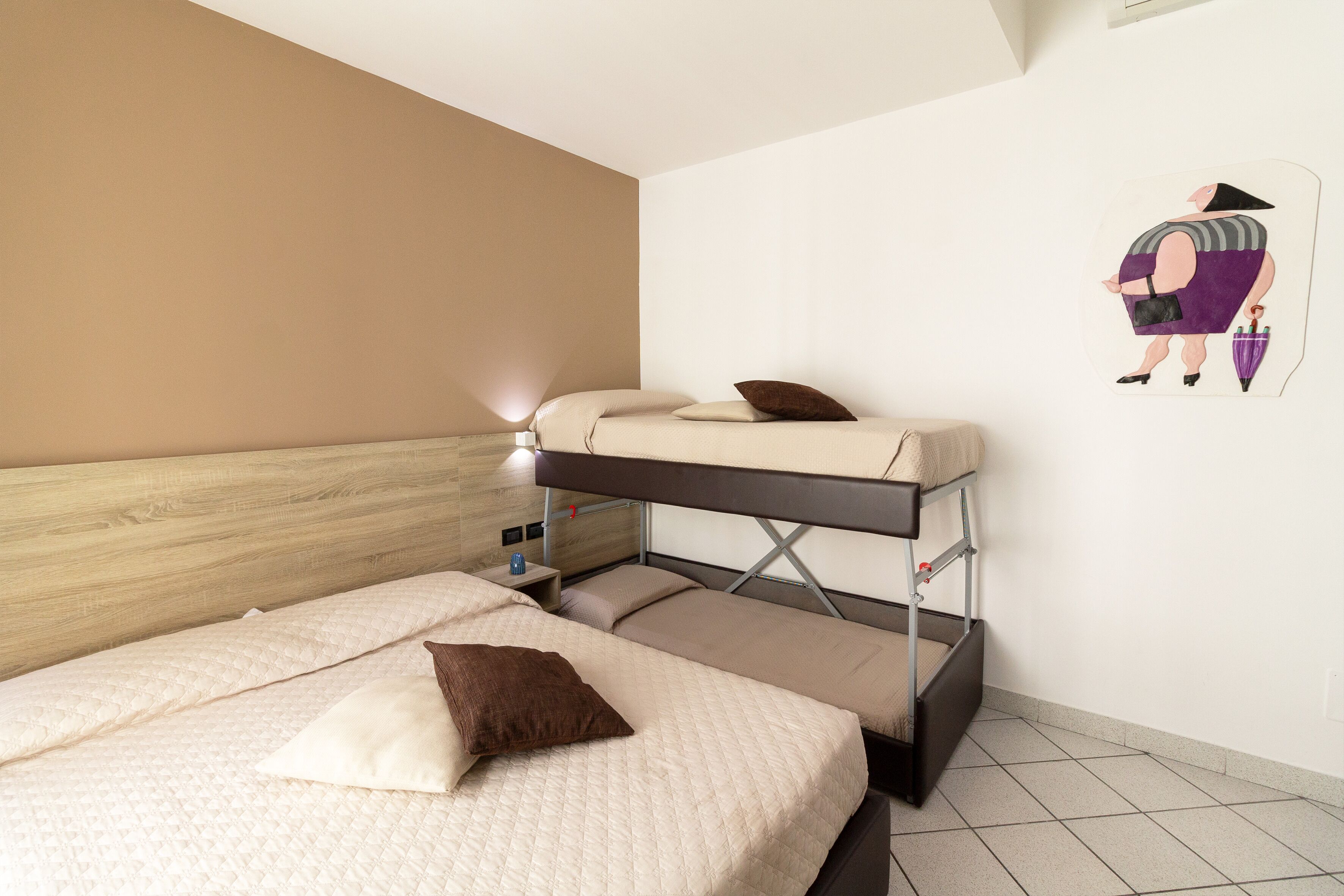 A bunk bed room with a wooden headboard, a small bedside table, and a wall-mounted artwork.