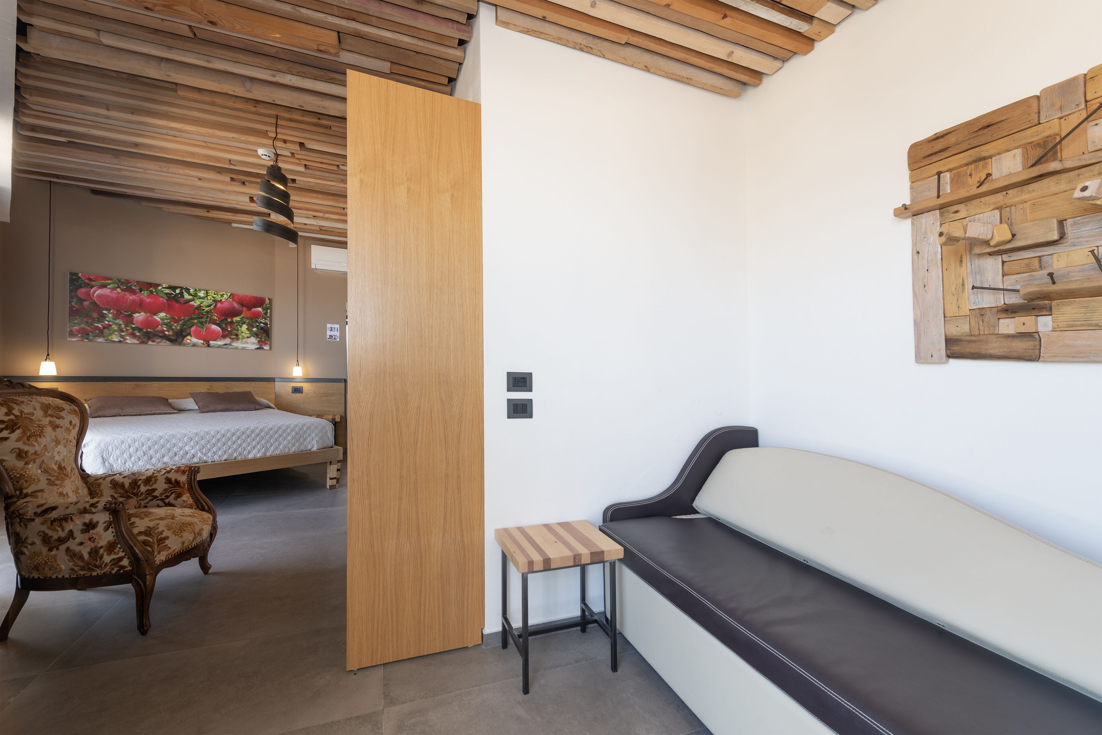 A modern bedroom with a bed, a wooden headboard, a bench, and a small table.