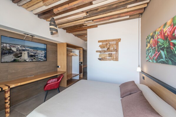 A modern bedroom with a wooden ceiling, a large bed, a desk, and a red chair. - Hotel da Romano (San Foca)