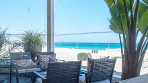 En balkon med udendørs siddepladser, udsigt til stranden og en stor plantekasse.