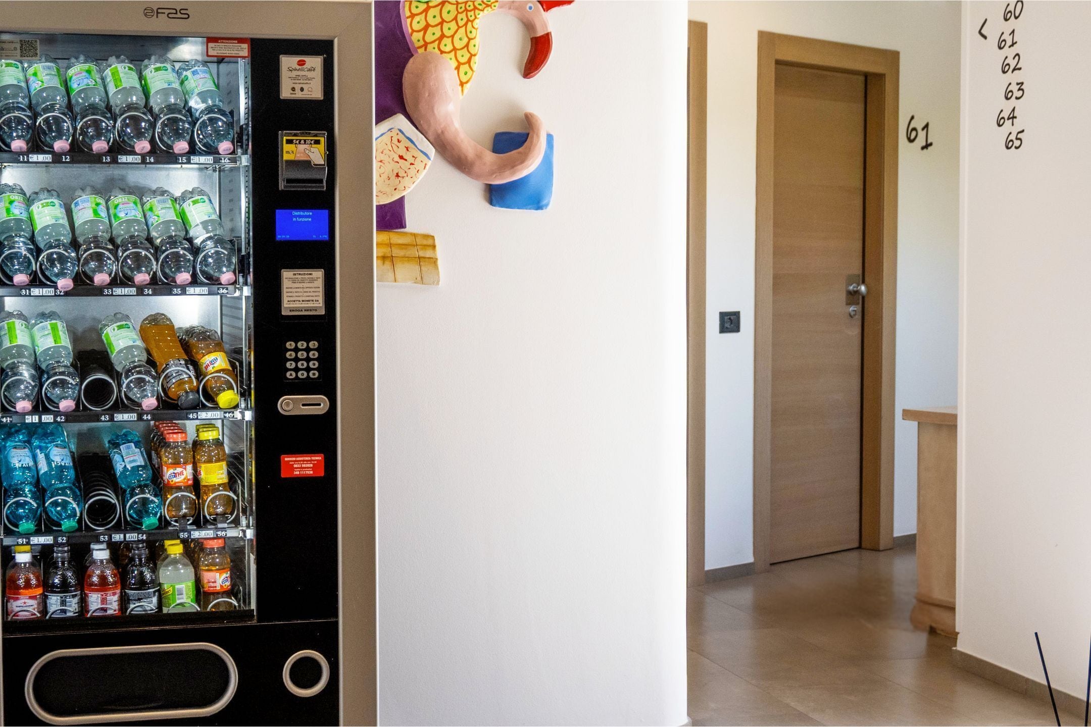 A vending machine with various beverages and a wall with a number sequence.