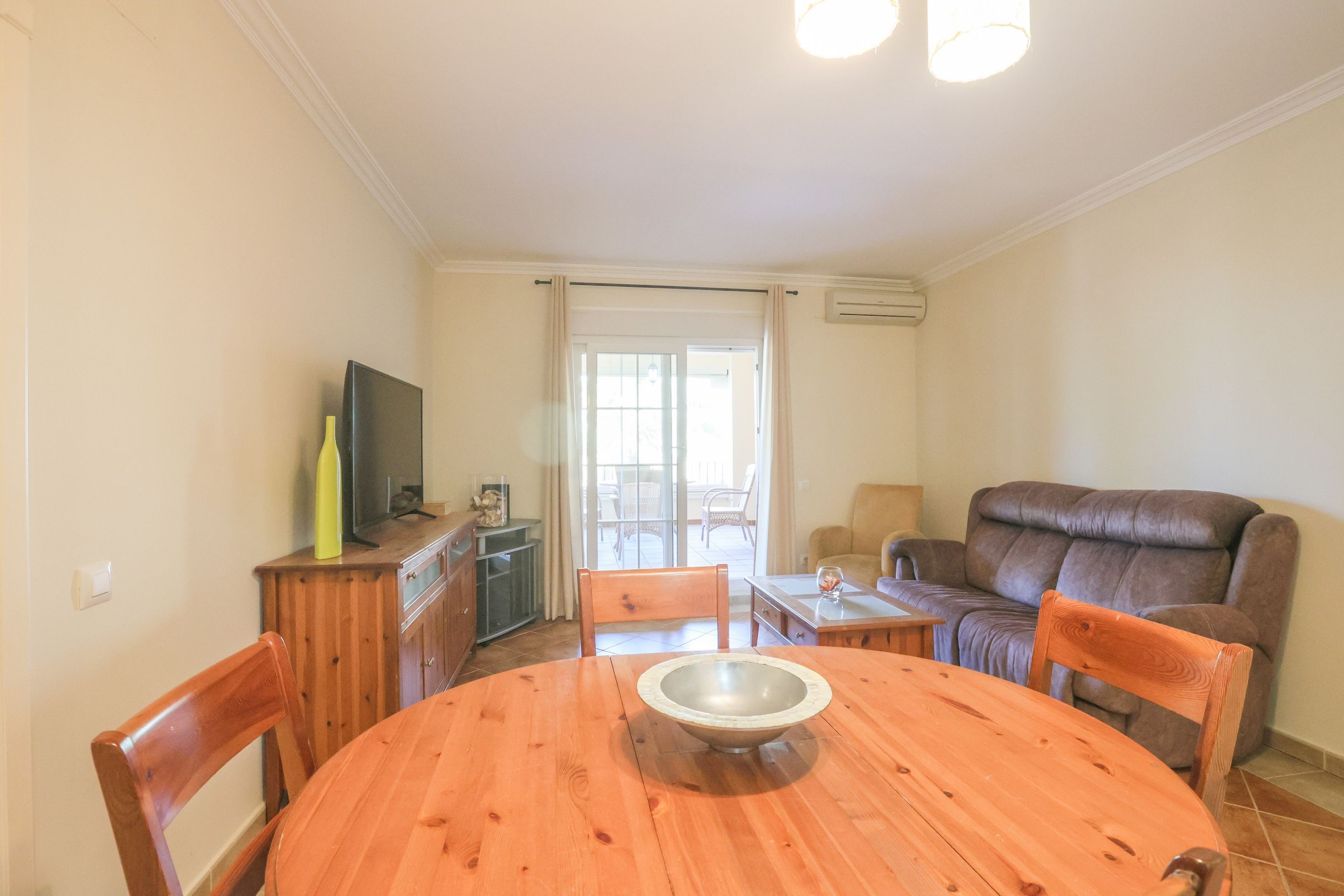 A dining area with a round table, chairs, a television, and a sofa.