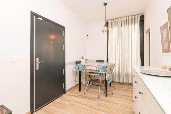 Une cuisine de taille réduite avec une table à manger, une porte noire et un plan de travail blanc.