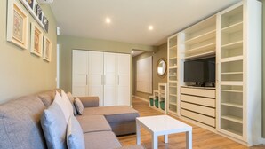 A living room with a grey sofa, white coffee table, and a large white shelving unit with a TV. - La Playa in Torremolinos (Torremolinos)