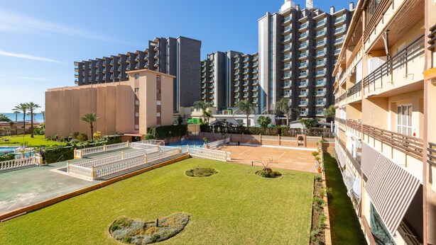 A hotel courtyard with a swimming pool, green lawns, and high-rise buildings in the background. - La Playa in Torremolinos (Torremolinos)