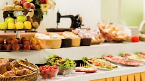 A buffet table with various food items including fruits, pastries, and salads. - MADAMA GUEST HOUSE (Florence)