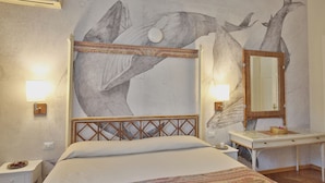 A bedroom with a large bed, a bedside table, a nightstand, a dresser, a mirror, and a wall mural of whales. - MADAMA GUEST HOUSE (Florence)
