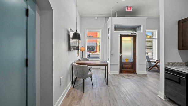 A modern kitchen with a dark countertop, a wooden dining table, and a gray chair.