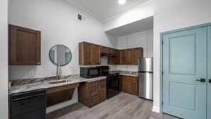 A modern kitchen with wooden cabinets, a stainless steel refrigerator, a microwave, and a dishwasher.