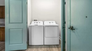 A laundry room with two white washing machines and a door.