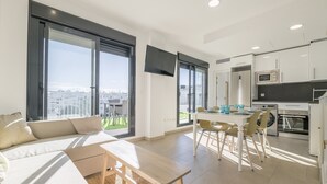 Eine moderne Wohnung mit Essbereich, Küche und einem großen Fenster mit Blick auf die Stadt.