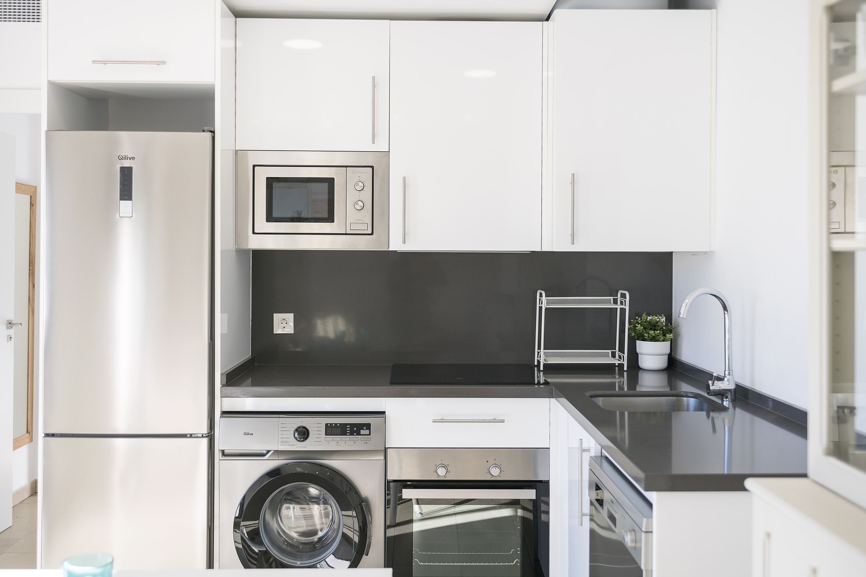Una cucina moderna con frigorifero in acciaio inossidabile, forno a microonde, forno e lavatrice.