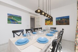 A dining area with a long table set for six, surrounded by chairs. There are paintings on the walls and a chandelier above the table. - Los Jandalos in El Puerto de Santa Maria (El Puerto de Santa Maria)